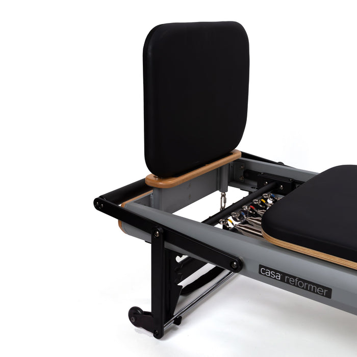 Padded jump board fitted upright at the foot end of a Peak Pilates casa reformer with an aluminium frame