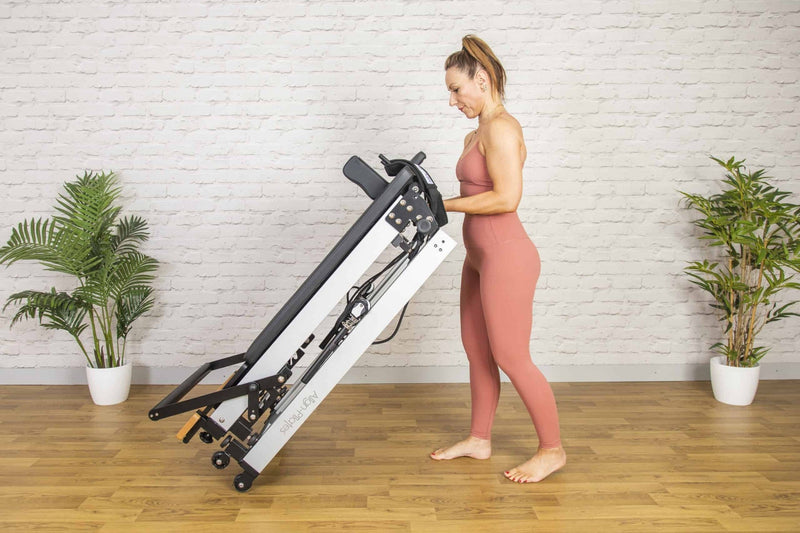 Align Pilates F3 Folding Reformer, woman lifting the frame to fold it