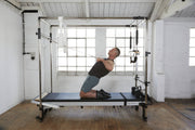 Align Pilates Full Cadillac Frame, man leaning back while holding the upper bar