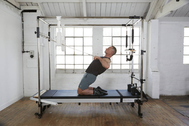 Align Pilates Full Cadillac Frame, man leaning back while holding the upper bar