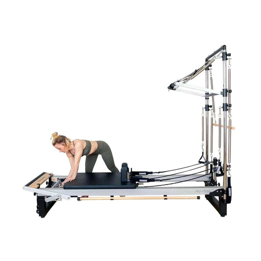 Align Pilates Half Cadillac Frame, side view on a reformer with a woman kneeling on the carriage
