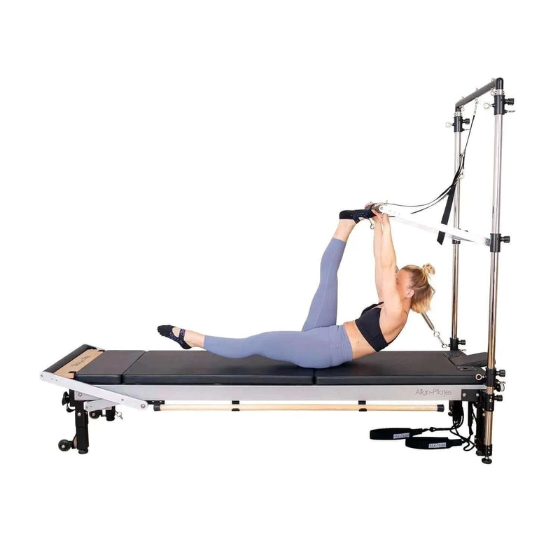 Align Pilates Half Cadillac Frame, woman stretching with a foot strap on a reformer bed
