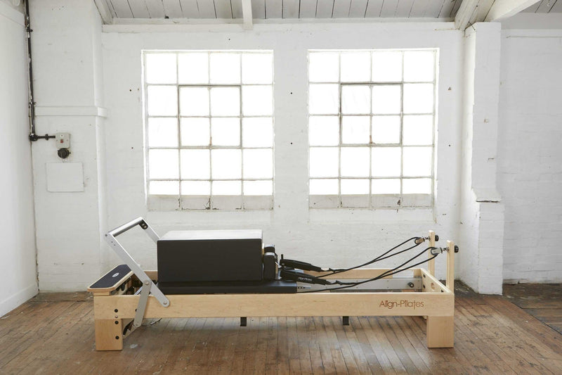 Align Pilates M8-Pro Reformer, angled studio view with a sitting box on the carriage