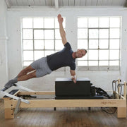 Align Pilates M8-Pro, instructor performing a side plank on the sitting box