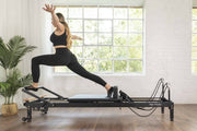 Align Pilates R8-Pro Reformer, woman in a standing lunge on the black frame