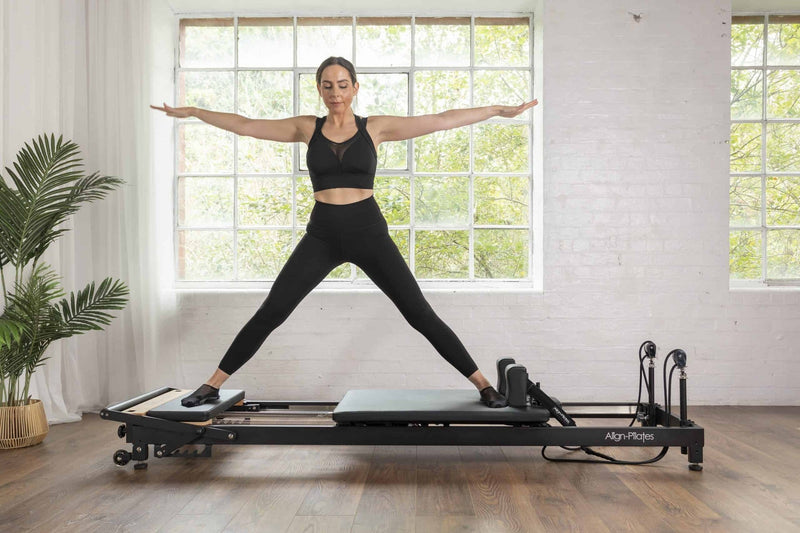 Align Pilates R8-Pro Reformer, woman balancing on the black frame