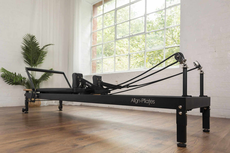 Align Pilates R8-Pro Reformer, black frame on raised legs by a window