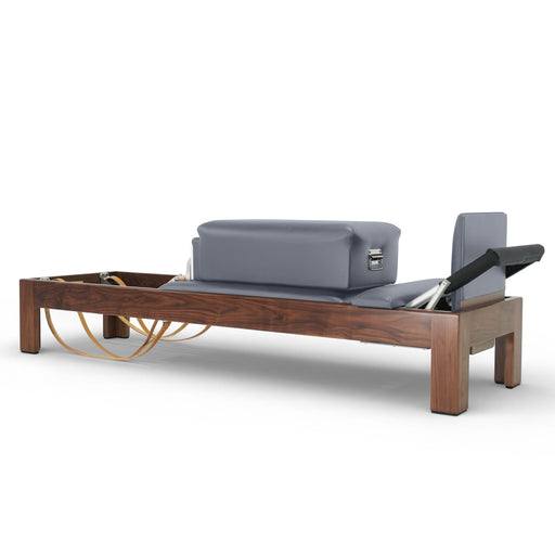 Elina Pilates Classic Dark Wood Reformer in walnut with sitting box, grey upholstery, angled studio view