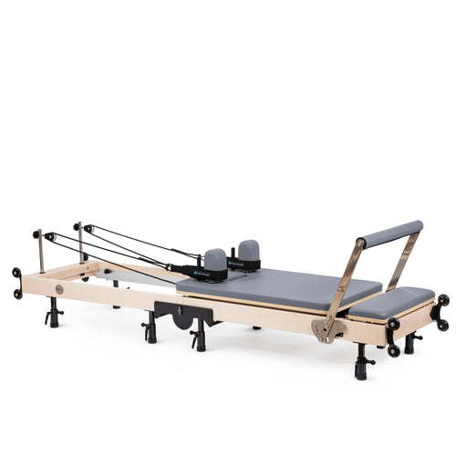Elina Pilates Fold Reformer set up, maple frame with grey upholstery, angled view