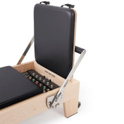 Elite Wood Reformer jump board stored upright behind the headrest, black